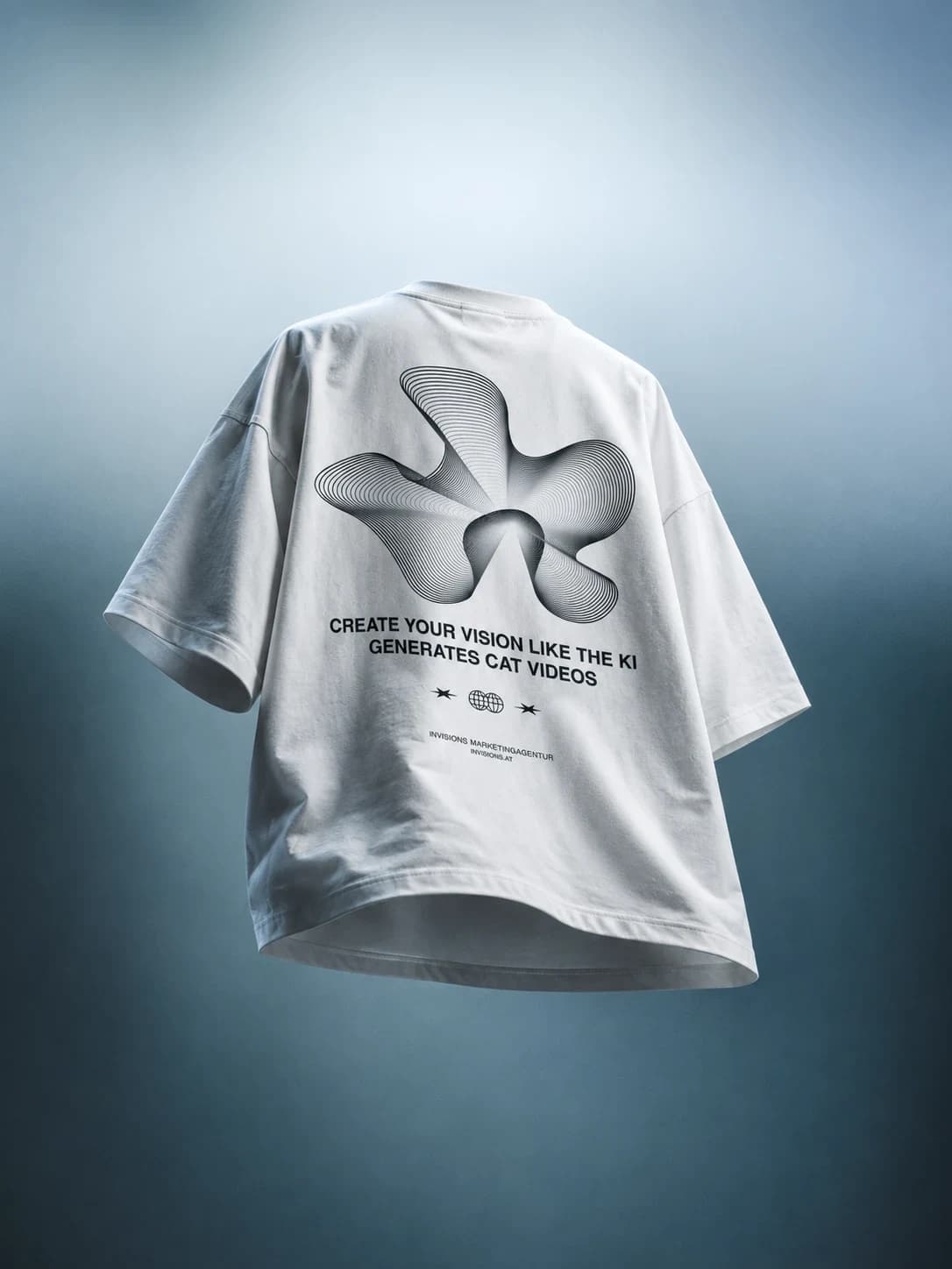 T-Shirt-Design für die Marketingagentur Invisions (Mockup): weißes T-Shirt von hinten vor blaugrauem Hintergrund mit einer Blütenform aus feinen Linien, darunter die Zeilen „Create your vision like the KI generates cat videos“ und „Invisions Marketingagentur“